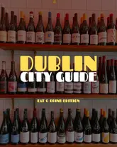 A graphic title card for a Dublin city guide featuring a background of wine bottles on shelves.