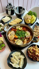 A high-quality food montage showcasing a 'Simmer Pot' that transitions into a hotpot, featuring various sides like squid, dumplings, and scallion pancakes.