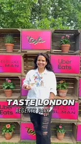A promotional lifestyle shot taken at the Taste of London festival in Regent's Park, featuring a visitor posing in front of a branded backdrop while holding a glass of wine.