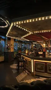 A wide-angle, atmospheric shot of the interior of Flight Club Victoria, focusing on the bar area with its signature decorative bulb lighting and moody, inviting aesthetic.