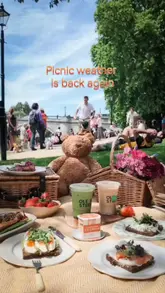 A short, aesthetic video featuring a picnic by the river, showcasing various food and drink items from Ole & Steen, including sandwiches, iced matcha, coffee, and Cinnamon Social ice cream.