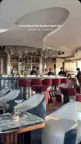 A short, high-quality promotional video for a luxury bar located in a London hotel. The video features a montage of sophisticated cocktails, including one served under a smoke cloche, and premium small plates like lobster tacos and wagyu hotdogs. The editing is smooth and aesthetic, focusing on the upscale interior and the presentation of the food and drink.
