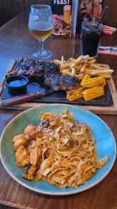 A couple visits TGI Fridays to try their new menu items and classic dishes, showcasing a variety of food including a combo platter, steak and ribs, pasta, and dessert in an energetic, fast-paced video.