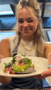 The video follows two creators attending a Mexican street food cooking class at a cookery school. It documents the process of making tlacoyos, from shaping the corn dough to topping the finished dish with avocado, salsa, and cheese. The tone is upbeat and educational, highlighting the hands-on nature of the experience.