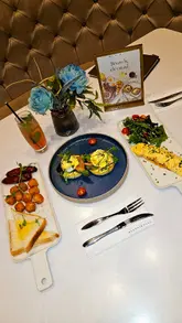 A short, music-led montage showcasing the interior decor and brunch offerings of a restaurant. The video transitions from exterior shots to the dining area, followed by close-ups of an omelette, eggs royale, and a chocolate cake, highlighting the presentation and textures.