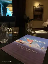 A clean, well-composed shot of a 10-course tasting menu at Six by Nico, focusing on the 'The Chippie' theme. The image effectively sets the scene for a high-end dining experience in a dimly lit, atmospheric restaurant setting.