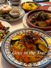 A high-angle, flat-lay shot of a table spread at a Moroccan restaurant, featuring various traditional dishes like tagine, couscous, and pastilla served in authentic ceramic bowls.