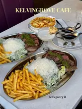 A flat-lay overhead shot of a 'summer roast' meal at Kelvingrove Cafe, featuring steak, fries, salad, a cocktail, and a side of mac and cheese.