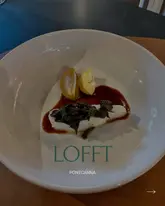 A minimalist, fine-dining style shot of a turbot dish served at Lofft in Pontcanna. The image features a single portion of fish topped with mushrooms and a sauce, presented on a large white plate, capturing the essence of a high-end tasting menu experience.