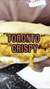 A food review video featuring two creators trying a spicy dip chicken burger and chicken strips at Toronto Crispy in Birmingham.