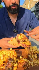A creator reviews the 'Cone Carnage' dish at Axe & Ember Smokehouse, featuring smoked brisket, ribs, and sausage served in a waffle cone filled with mac and cheese. The video includes a taste test and commentary on the quality of the smoked meats.