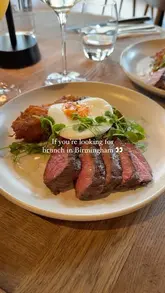 A short, aesthetic montage showcasing a steak and egg brunch dish and a peach spritz at a restaurant in Birmingham, followed by brief shots of the venue's interior.