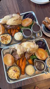 A montage showcasing a large Sunday roast sharing platter at Woodfalls Inn, featuring various meats and sides, followed by brief shots of the pub's interior and exterior.