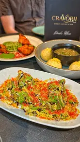 A review of Cravorii, a new Indian restaurant in Bury, showcasing a variety of small plates, signature curries, and desserts. The video highlights the high quality of the food presentation and the inviting atmosphere of the venue.