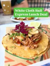 A close-up, eye-level shot of a chicken taco topped with red cabbage and pineapple salsa, served on a branded paper liner, with a green text overlay promoting a lunch deal.