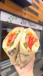 A short, handheld video showcasing a freshly made Italian schiacciata sandwich held in front of the shop front.