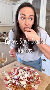 A recipe tutorial video demonstrating how to make 'Greek Style Loaded Nachos' using pita bread, minced chicken, tzatziki, and fresh toppings. The creator guides the viewer through the preparation and assembly process with clear text overlays.