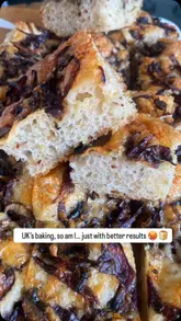 A short, handheld video showcasing a freshly baked mushroom and onion focaccia. The video focuses on the texture and appearance of the bread, with the creator holding a slice to demonstrate the crumb and toppings.
