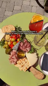 A short, engaging reel promoting a deli in Manchester, showcasing their charcuterie boards and spritz cocktail offer. The video uses a mix of handheld shots to create an inviting, social atmosphere, effectively highlighting the venue's outdoor seating and food/drink menu.