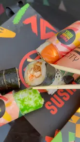 A short, handheld video showcasing a 'push-up' sushi roll concept from Sushi City. The video features close-up shots of various sushi rolls being held and dipped in soy sauce, highlighting the convenience of the packaging.