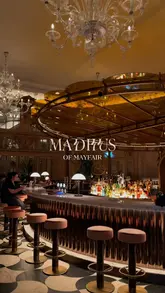A montage video showcasing the interior and various dishes at Madhu's of Mayfair. The video features slow, cinematic pans of the restaurant's decor, including chandeliers and the bar area, followed by close-ups of several Indian dishes such as chaat, tandoori salmon, kebabs, curry, and biryani.