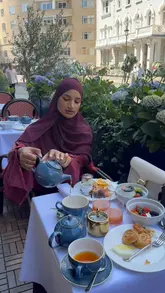 A short, aesthetic video featuring a woman enjoying a breakfast spread on a sunny outdoor terrace in London, focusing on the relaxing atmosphere and food presentation.