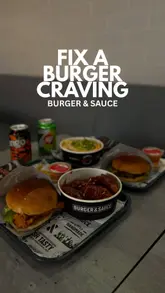 A short, informative review of a visit to Burger & Sauce, highlighting their 'Double Up' deal which includes two burgers, two fries, and two drinks. The video features shots of the venue interior, the menu board, and close-ups of the food items, including chicken and beef burgers, BBQ wings, and onion rings.