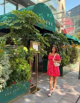 A bright, well-composed portrait of a woman standing in front of The Ivy restaurant in Cardiff, showcasing the venue's exterior branding and outdoor seating area.