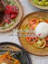 A high-quality, overhead flat-lay shot of several plates of food, including a burrata salad with tomatoes, on a marble table. The image is bright, well-composed, and clearly intended to showcase the aesthetic appeal of the dishes for a date night setting.
