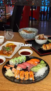 A creator visits Samsi, identified as Manchester's oldest sushi restaurant, providing a tour of the traditional Japanese-style seating and a review of various dishes including kushiyaki, gyoza, takoyaki, an omakase platter, katsu curry, and sorbet.