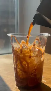 The video demonstrates how to make an iced coffee at home using beans from a coffee subscription service. It includes a screen recording of the subscription website and a step-by-step process of brewing coffee with a moka pot, frothing milk, and assembling the drink.
