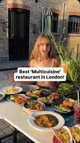 A creator reviews a plant-based restaurant in Camden Market, showcasing a wide variety of dishes from multiple cuisines including American, Caribbean, and Indian. The video features the creator trying various items, highlighting the texture of the mock meat, and providing a discount code for viewers.