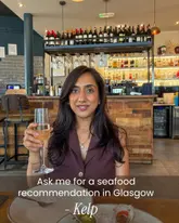 A portrait of a woman holding a glass of champagne in a restaurant setting, with text overlay promoting a seafood restaurant in Glasgow.
