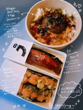 An overhead flat-lay shot of takeaway Japanese food, specifically a Wagyu beef patty donburi and two sushi tacos (eel/cucumber and salmon/avocado), presented in their takeaway containers.