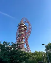 A clear, daylight shot of the ArcelorMittal Orbit structure in London against a bright blue sky.
