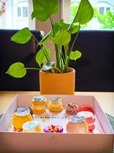 A high-angle shot of a gift box filled with assorted macarons, featuring personalized edible photo toppers. The macarons are vibrant and well-arranged, clearly intended as a birthday gift.