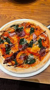 A short vlog-style video showcasing a casual dining experience at Bella Italia, featuring a non-alcoholic spritz, bruschetta, and a vegan vegetable pizza.