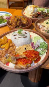 A montage of various Southeast Asian dishes served on wooden plates, featuring beef brisket, chicken rice, and other street food-style items. The video focuses entirely on the food presentation on the table.