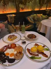 A flat-lay photograph of a brunch spread at The Glade in Sketch London, featuring various breakfast items including French toast, eggs benedict, a full English breakfast, granola, and drinks.