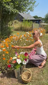 A creator visits a flower farm in Kent, demonstrating the process of picking seasonal flowers and arranging them into a bouquet. The video captures the aesthetic, slow-paced nature of the activity in a sunny, outdoor setting.