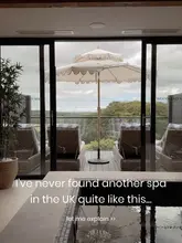 A high-quality, atmospheric shot of a spa pool looking out onto a scenic, green landscape through large glass doors. The image effectively uses natural light to create a relaxing, luxurious mood, inviting the viewer to experience the venue.