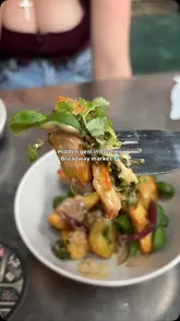 A montage video showcasing a variety of small plates and cocktails at The Brasa Club in Tooting Broadway Market. The video features close-up shots of dishes like savoury doughnuts, crispy ravioli, and chips, alongside cocktail preparation and consumption.