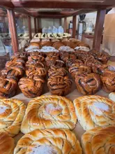 A close-up, eye-level shot of a bakery display case filled with rows of various pastries, including plaited croissants and Jaffa cakes.