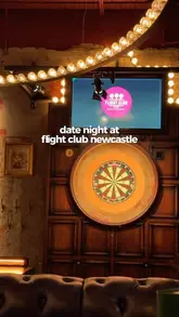 A moody, atmospheric shot of a dartboard at Flight Club Newcastle, effectively showcasing the venue's interior aesthetic and suitability for a date night.