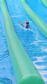 A fast-paced montage showcasing various activities at the Summertopia event at Avon Valley Park, including water slides, bouncy inflatables, go-karts, and animal interactions, aimed at families.