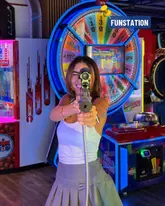 A vibrant, high-energy promotional shot taken at Funstation, featuring a person actively engaged with an arcade game. The image effectively communicates the fun, competitive, and interactive nature of the venue, using the arcade's neon lighting to create an immersive atmosphere.