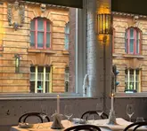 A beautifully composed, atmospheric shot of a restaurant interior, focusing on a neatly set table with candles and a view of the historic building opposite, capturing a sophisticated and inviting mood.