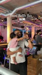 A vlog-style video showcasing a visit to Boom Battle Bar in Ealing, highlighting the interactive darts games and the food menu.
