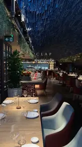 A short, aesthetic montage showcasing the interior and menu of CLAP in Knightsbridge, London. The video features slow, smooth pans of the dining area, close-ups of various dishes including sushi and cocktails, and glimpses of the open kitchen, set to music with text overlays.