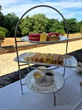 A high-quality, bright image of an afternoon tea stand set against an outdoor garden backdrop at a luxury hotel.